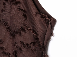 Gros plan sur le tissu texturé marron foncé avec détails de franges et zip invisible