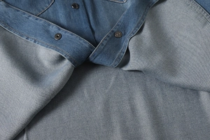 Detailed close-up of blue denim shirt fabric texture and black metallic snap buttons