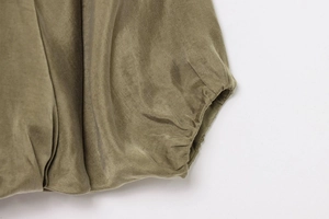 Macro shot of green bomber jacket elastic cuff featuring smooth satin fabric and fine stitching