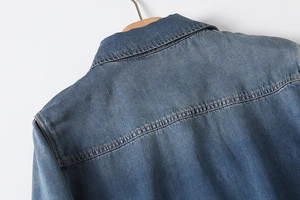 Detail of the back collar and shoulder stitching on a washed blue denim shirt