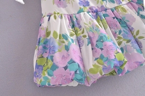 Detail of floral chiffon fabric featuring ruffles, smocked texture, and purple flowers