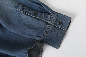 Detailed view of deep blue washed denim shirt cuff featuring black round buttons
