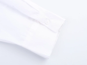 Vue détaillée du poignet d'une chemise en popeline blanche avec bouton et coutures fines