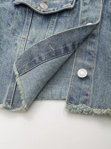 Light blue denim jacket featuring raw hem detail and silver metal buttons with jeans engraving