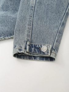 Light blue denim jacket detail featuring raw edges and silver metal JEANS button
