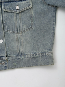 Detail shot of vintage denim jacket with distressed textures and metal buttons