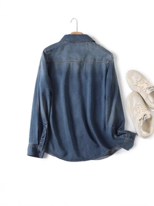 Back view of a vintage long sleeve denim shirt in washed blue with a curved hem