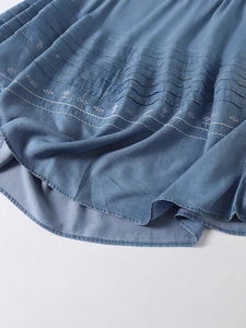 Spring denim dress with layered pleats and white geometric embroidery details