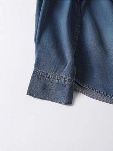 Classic dark blue denim shirt for women with detailed stitching and curved hemline view