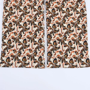 Detail of printed wide-leg pants hem featuring abstract floral pattern on textured fabric
