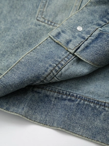 Detailed macro view of vintage blue denim fabric with yellow stitching and metal button