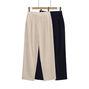 Détail de pantalons droits à taille haute en beige et noir avec des cintres en bois