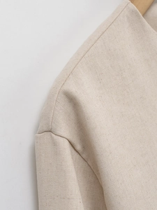 Detail of shoulder seam and linen texture on a beige tweed style short jacket