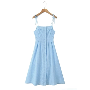 Detail of light blue embroidered dress featuring bow straps and delicate ruffle neckline