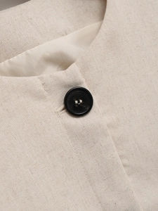 Close-up of linen texture, neck collar, and black button on light beige summer jacket