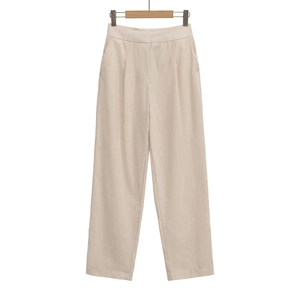 Détail du pantalon beige à taille haute, jambe droite avec plis et poches latérales