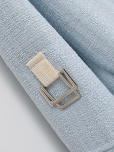 Detail of light blue tweed fabric with silver metal buckle and ivory ribbon texture