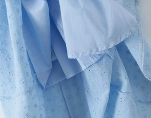 Detail of light blue daisy embroidery and inner lining on a summer dress fabric