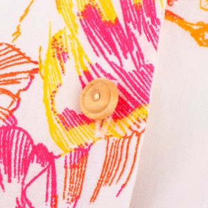Gros plan du tissu de la robe d'été avec imprimé floral et détail de bouton en bois
