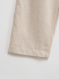 Gros plan détaillé du pantalon en lin beige montrant les coutures de l'ourlet et le tissu