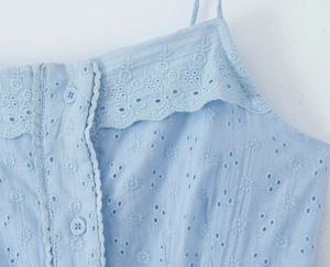 Detail view of light blue cotton camisole with floral embroidery and hollow lace edges