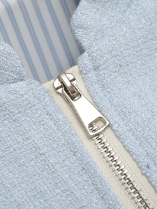 Detail of light blue tweed fabric with silver zipper and sparkling metallic threads