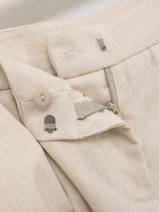 Vue détaillée de la taille du pantalon beige avec bouton et texture du tissu