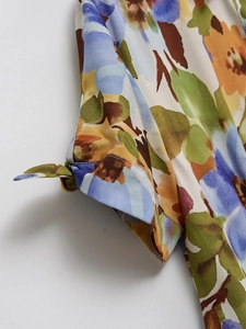 Detailed view of short sleeves with elegant knot design and vibrant floral print