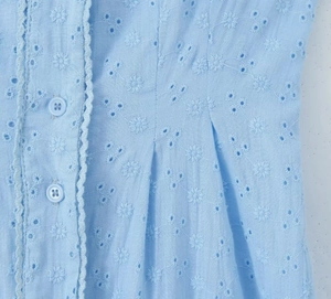 Close-up of light blue summer dress with floral eyelet embroidery and decorative buttons
