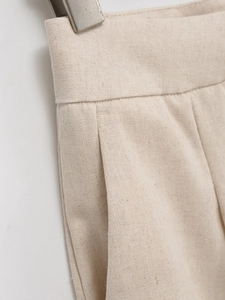 Détail du pantalon en coton beige à taille haute avec plis et poches latérales