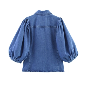Détail du haut en jean bleu montrant les manches bouffantes et les coutures au dos
