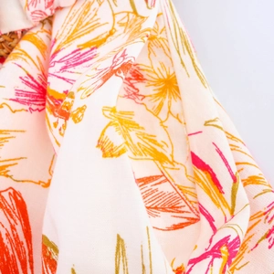 Gros plan sur le tissu léger à imprimé floral tropical aux fleurs orange et jaunes vives