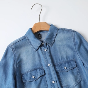 Detailed macro view of denim shirt collar with Foxy word brand label and pocket stitching