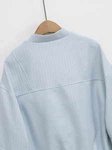 Macro shot of light blue tweed texture on the back collar and shoulders of a jacket