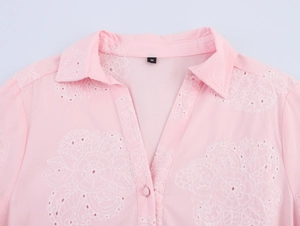 Detail of pink summer dress featuring delicate white lace floral embroidery and collar