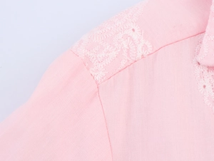 Detailed close-up of white floral embroidery on pink cotton summer mini dress shoulder