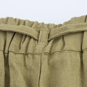 Detailed close-up of elastic ruffled high waistband with drawstring on linen trousers