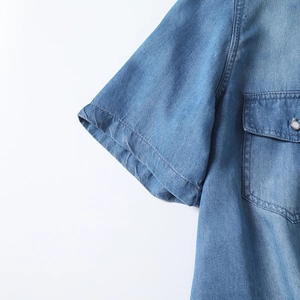 Detail of blue tencel denim shirt featuring metal snap buttons and chest pocket texture