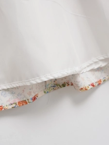 Detailed view of the white dress hem showing colorful floral lining and stitching
