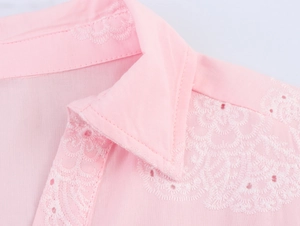 Detailed view of pink mini dress featuring white eyelet lace embroidery and collar detail