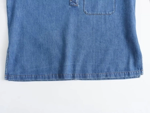 Detalle del dobladillo de chaqueta vaquera con costuras doradas y bolsillo frontal
