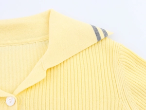 Macro detail of ribbed knit collar with contrast stripes and button on yellow cardigan