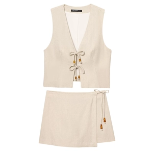 Detail view of beige linen set showing V-neck vest with wooden beads and wrap skirt tie