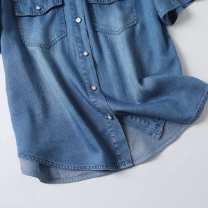 Detailed view of dark blue tencel denim shirt with metal buttons and flap pockets