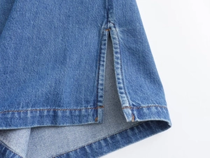 Detalle del dobladillo con abertura en conjunto de mezclilla azul con costura naranja