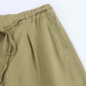 Detail of olive green linen trousers featuring elastic waistband and drawstring