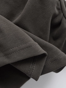 Detailaufnahme von dunkelgrauem Stoff mit präziser Doppelnaht am Saum des T-Shirts