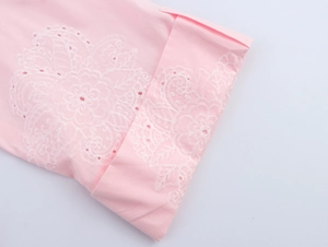 Close-up of pink fabric with white floral embroidery and delicate eyelet detailing