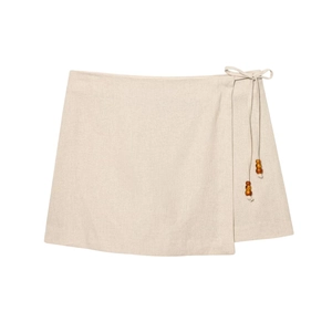 Detail of oatmeal linen wrap skirt with decorative wooden beads and waist tie