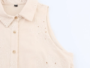 Detailed close-up of floral embroidery and eyelet texture on a beige sleeveless dress